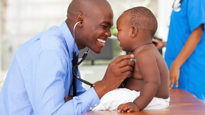 African-male doctor examining baby boy. Photo.Think Sock.